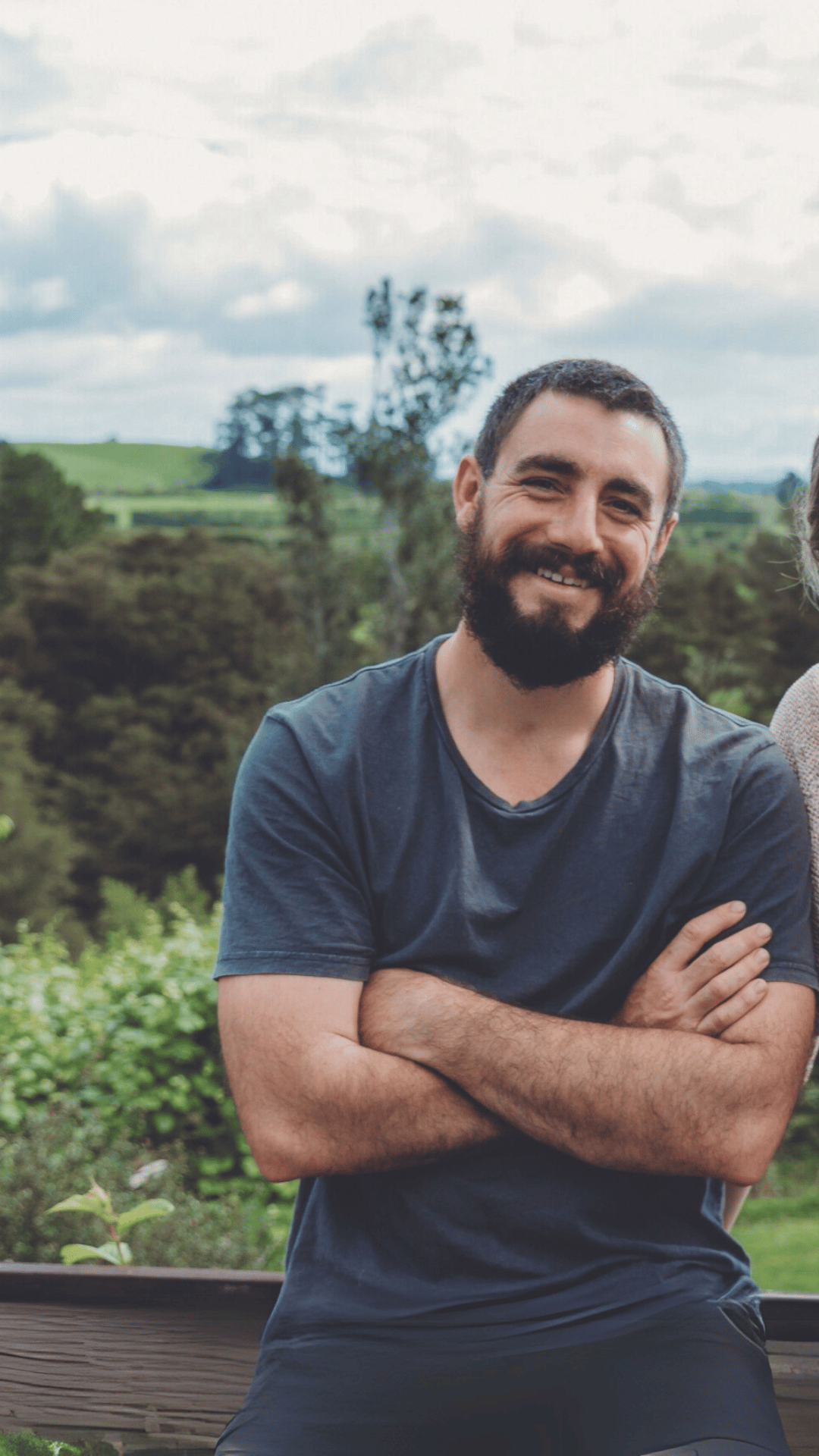 Woman and man in casual clothing against a rural backdrop,