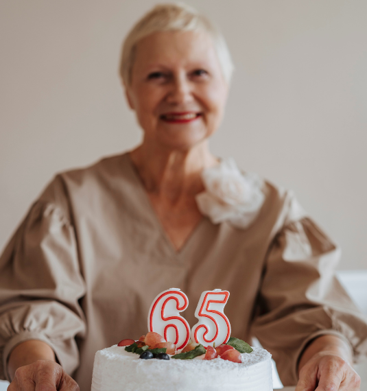Women with a birthday cake with 65 in candles to represent the changing face of retirement withdrawals and fund type| Generate