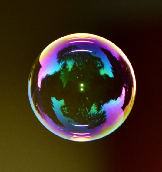 A bubble with a prism of colour through it on a black background to represent the topic of a possible AI bubble