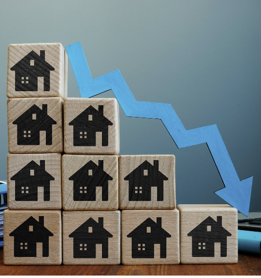 A pile of blocks in descending order with houses on them and a blue downwards arrow to represent falling house prices | Generate