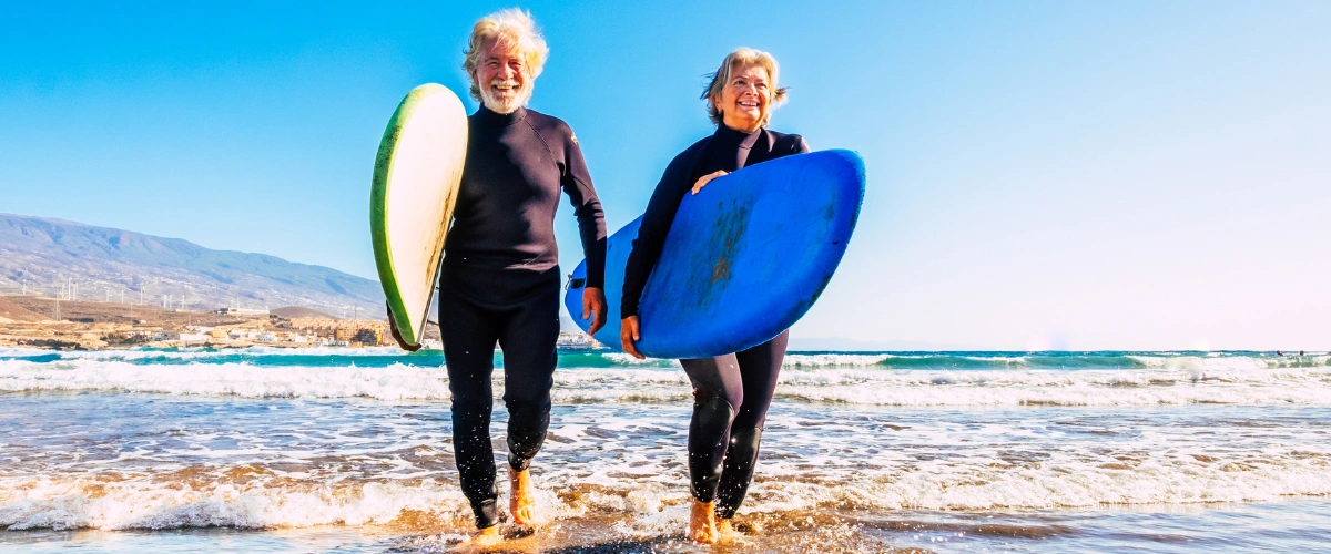 Retired couple on the beach with surfboards