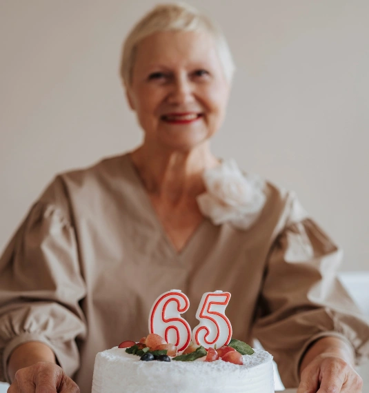 Women with a birthday cake with 65 in candles to represent the changing face of retirement withdrawals and fund type| Generate