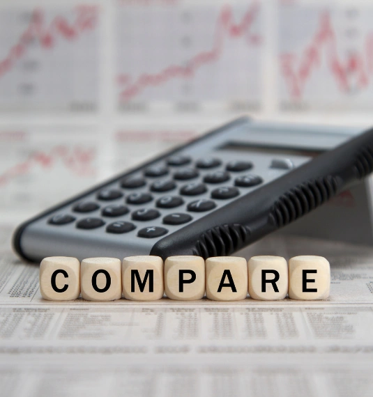 A calculator and Scrabble tiles with the letters spelling "compare" to represent comparisons of average KiwiSaver balances for different ages in New Zealand.