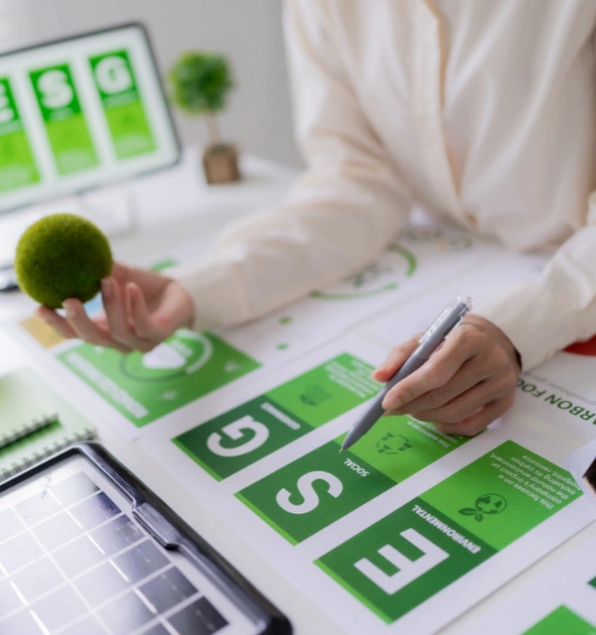 A woman holds a pen and looks at files with the words ESG on them in green to represent responsible investing and ESG considerations as part of a high-performing investment strategy