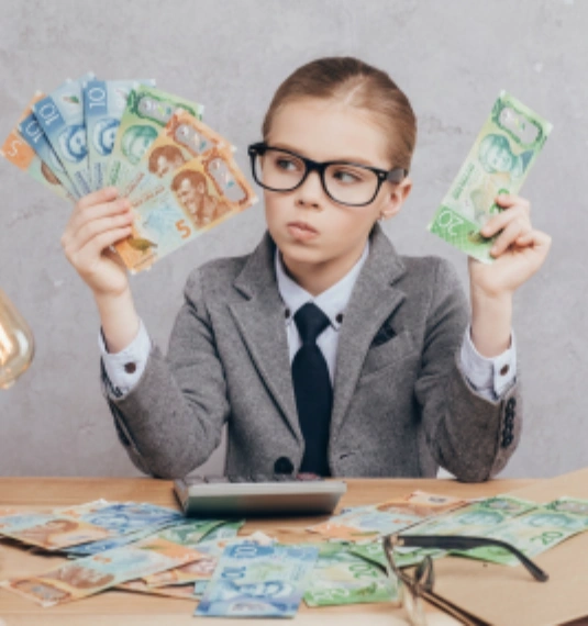 A young girl aged about 7 wearing a business suit and holding New Zealand money to represent the question should my child work in finance? and the related themes of trust, retirement savings and advice