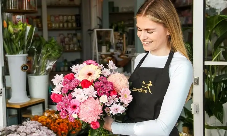 florist with a beautiful flower bouquet & smiling
